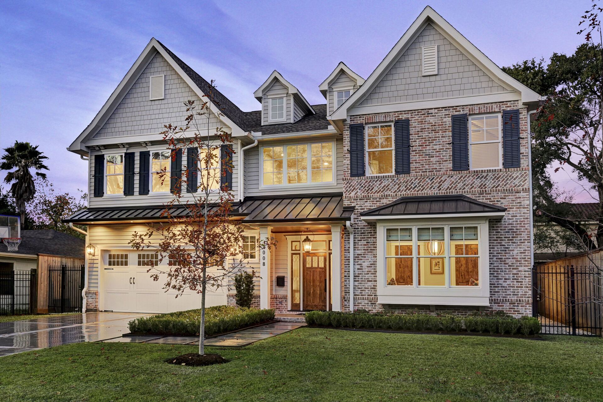 A large white brick house with blue shutters is sitting on top of a lush green lawn.
