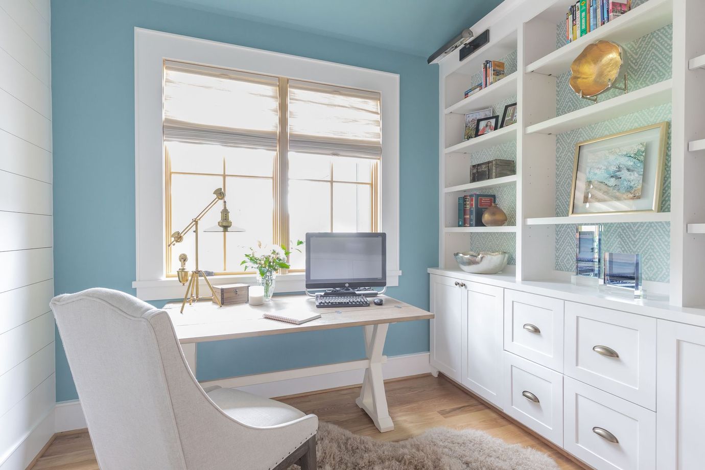 A home office with a desk , chair , computer and shelves.