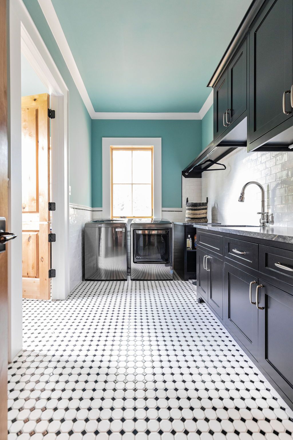 A laundry room with black and white tile floors and blue walls.