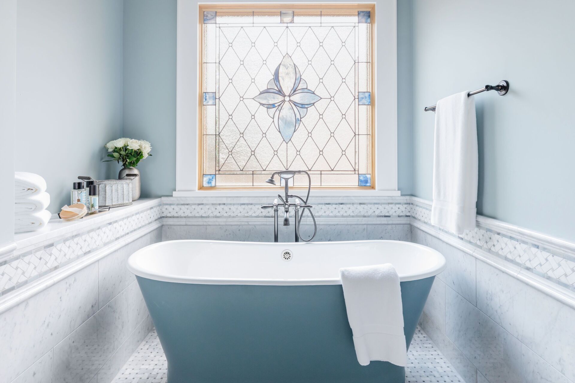A bathroom with a bathtub and a stained glass window.