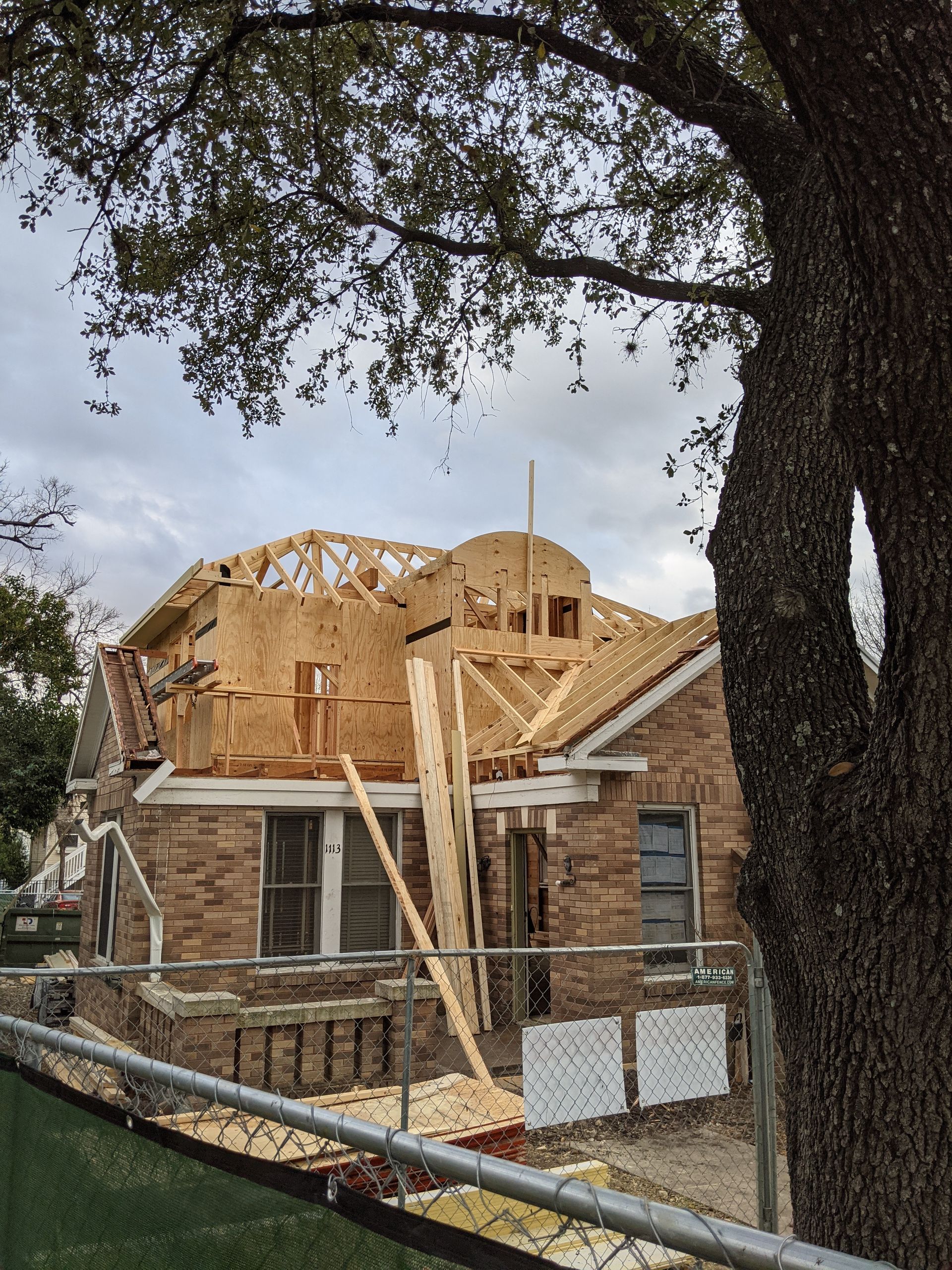 A house that is being built with a tree in the foreground