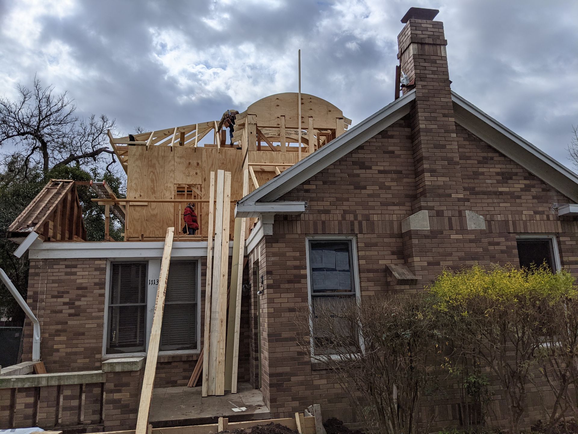 A brick house is being remodeled with a wooden roof and chimney.