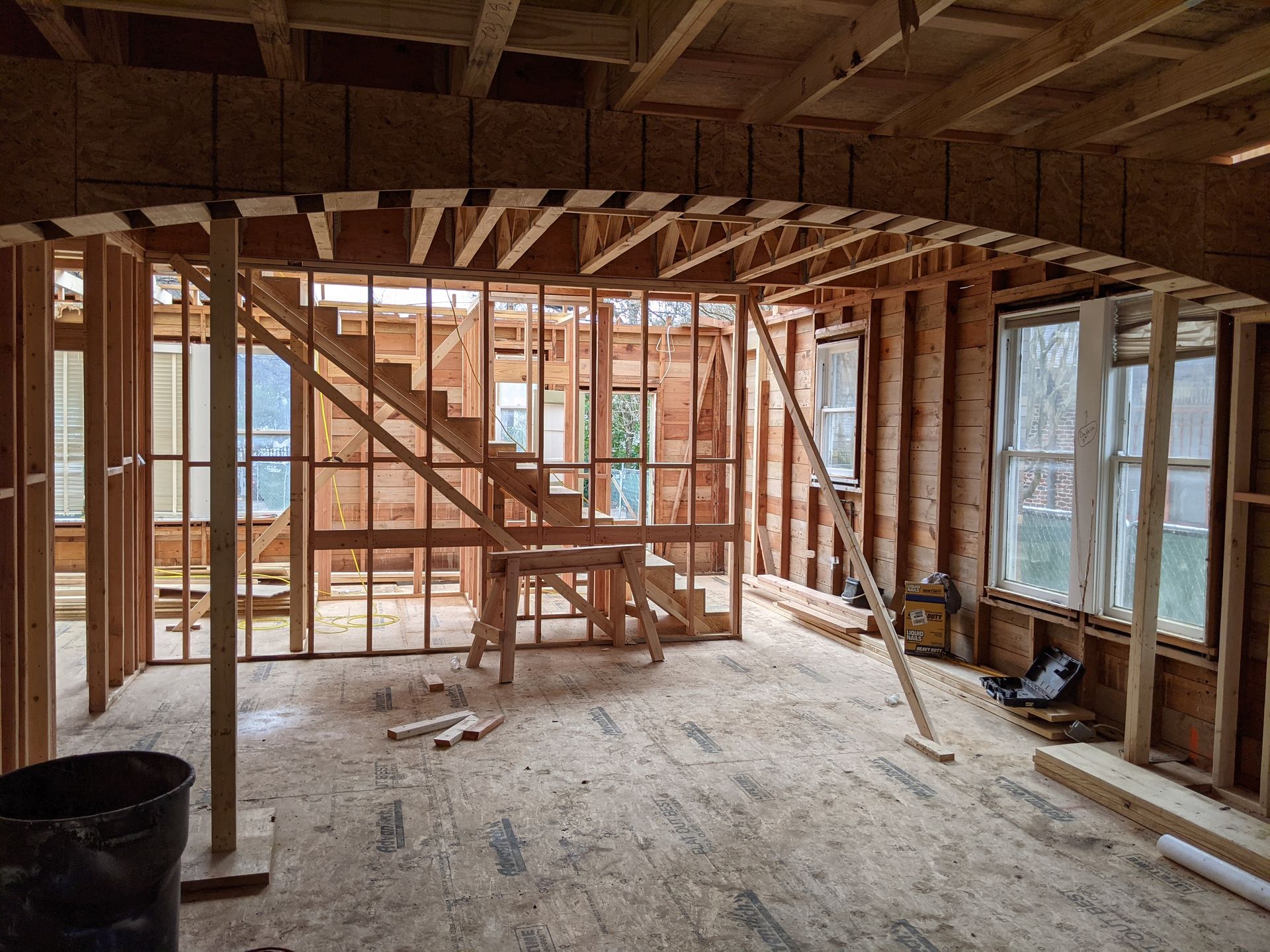 A room under construction with a staircase and windows.