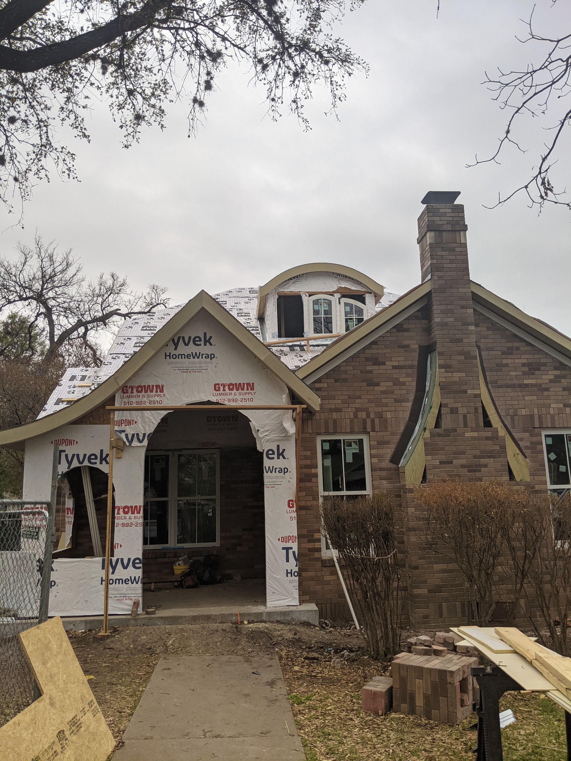 A brick house is being remodeled with a roof and chimney