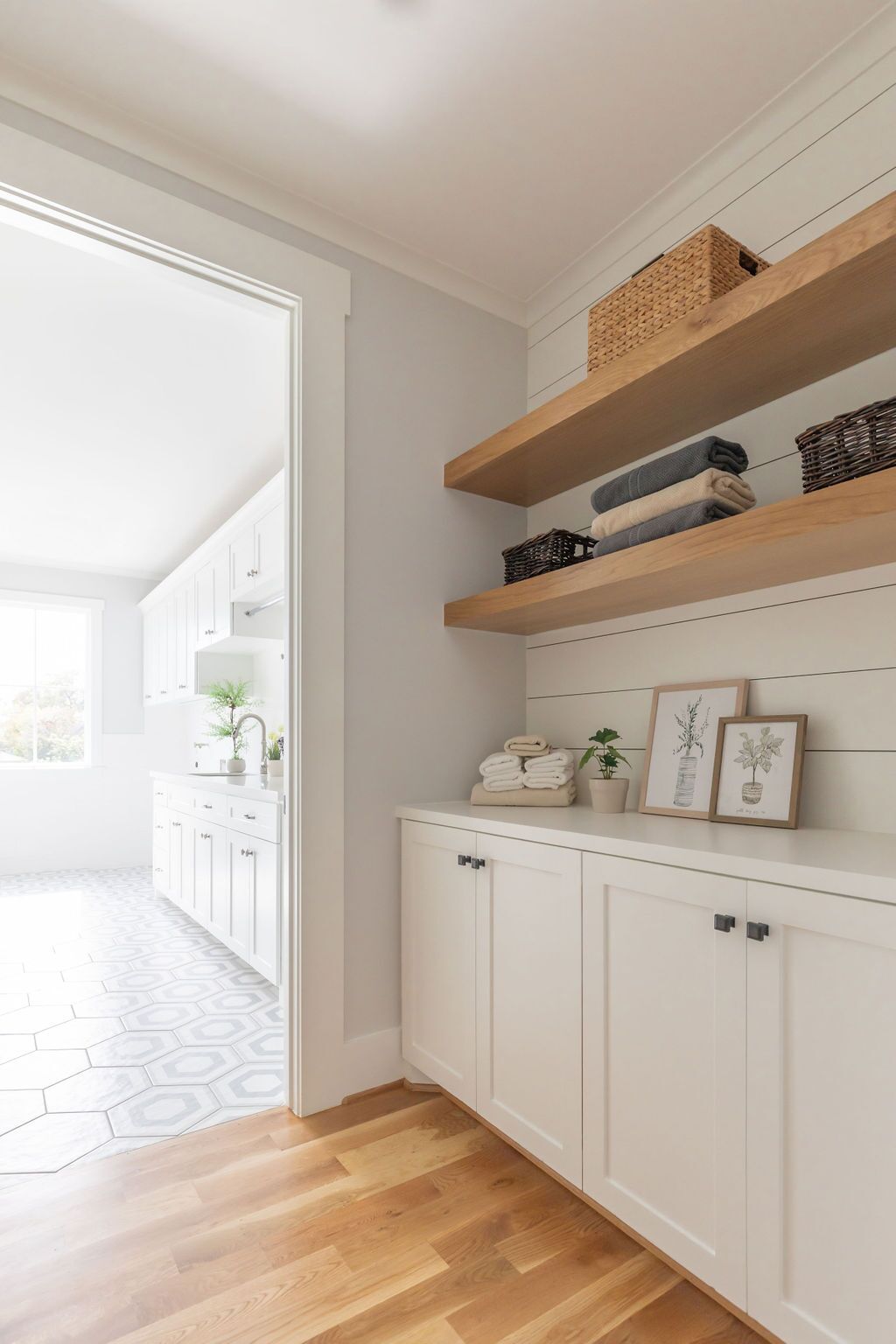 A laundry room with white cabinets and wooden shelves.
