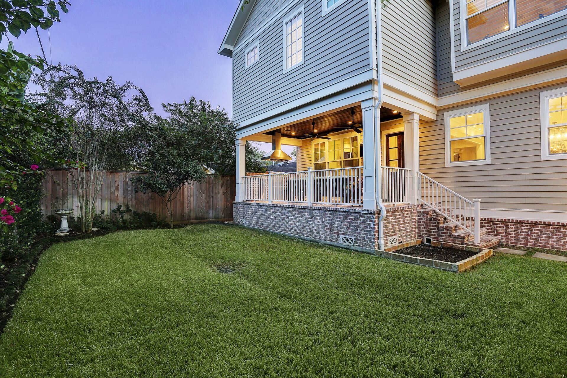 The backyard of a house with a large lawn and a porch.