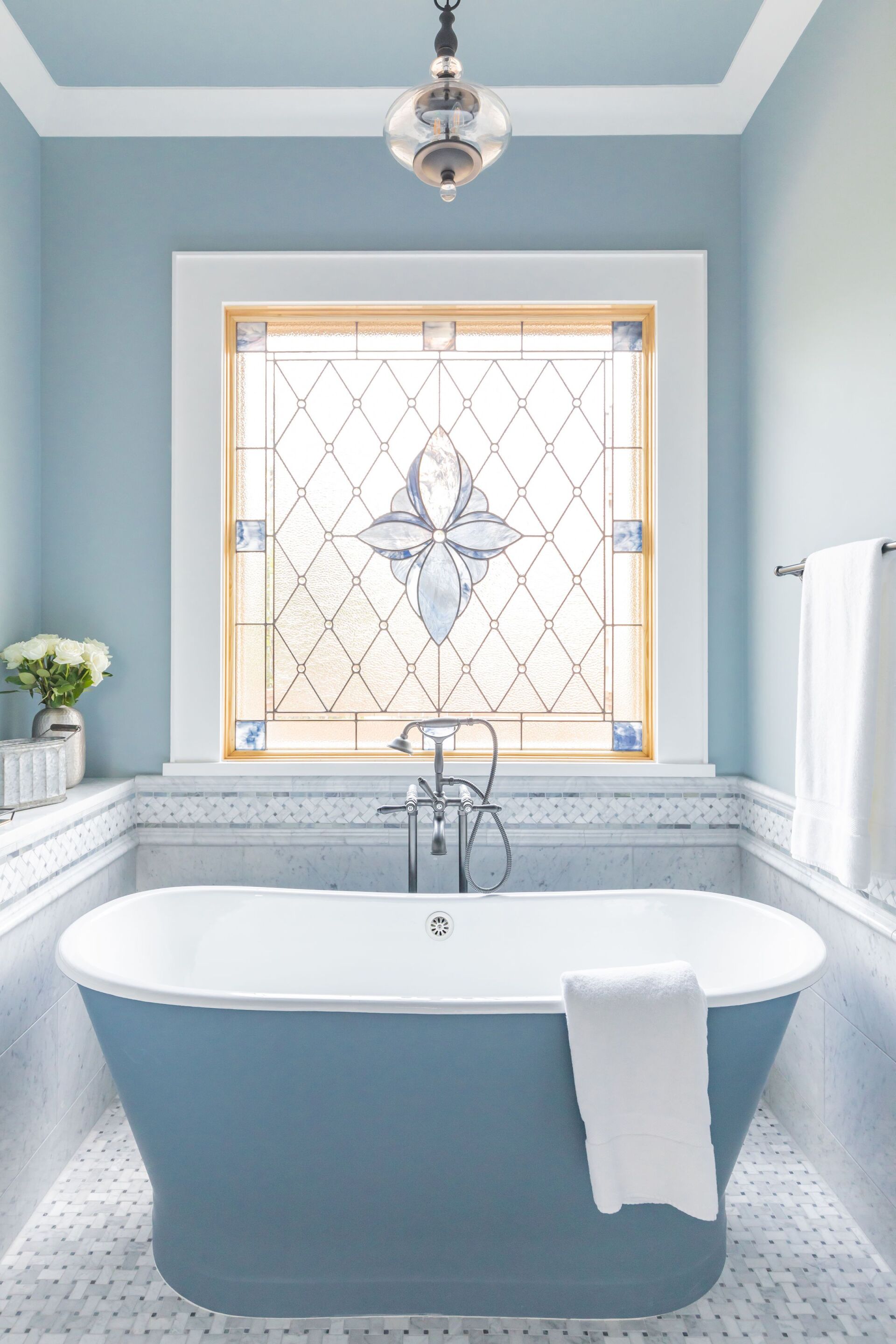 A bathroom with a blue tub and a stained glass window