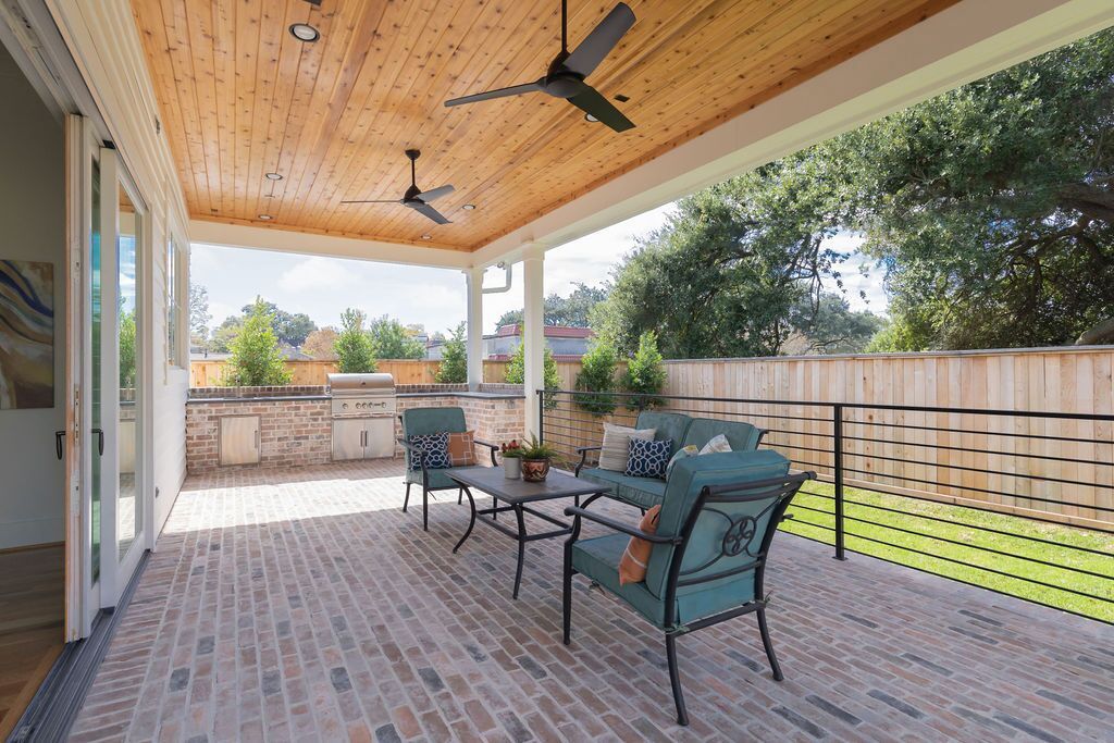 A patio with a wooden ceiling and a ceiling fan.