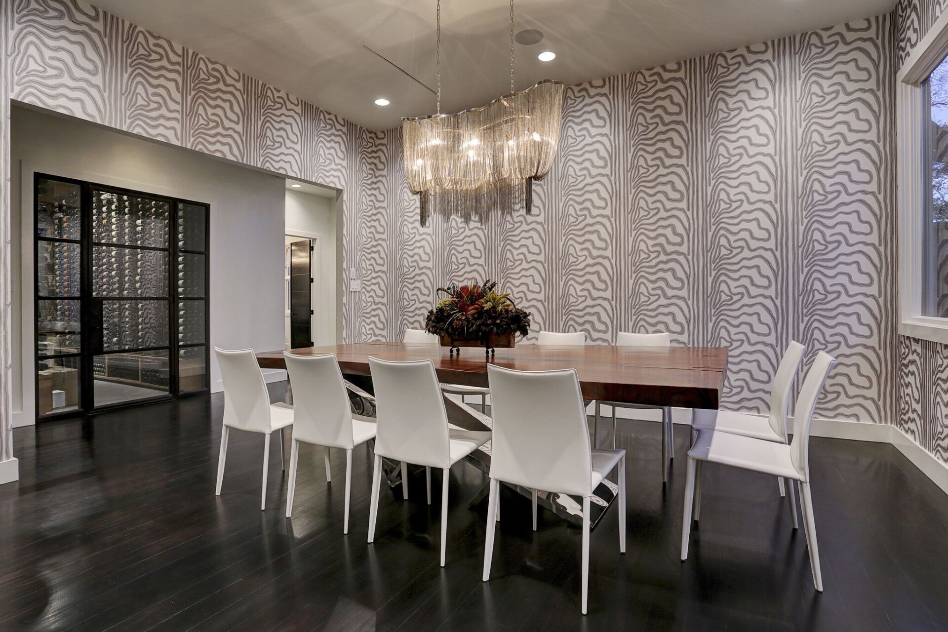A dining room with a long table and white chairs