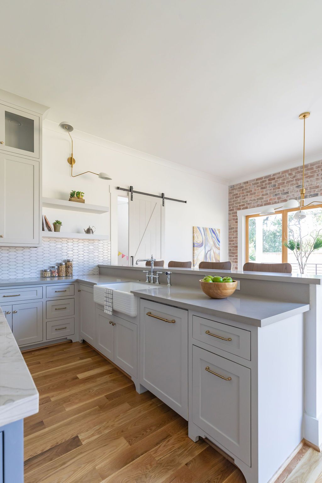 A kitchen with white cabinets and wooden floors and a sliding barn door.