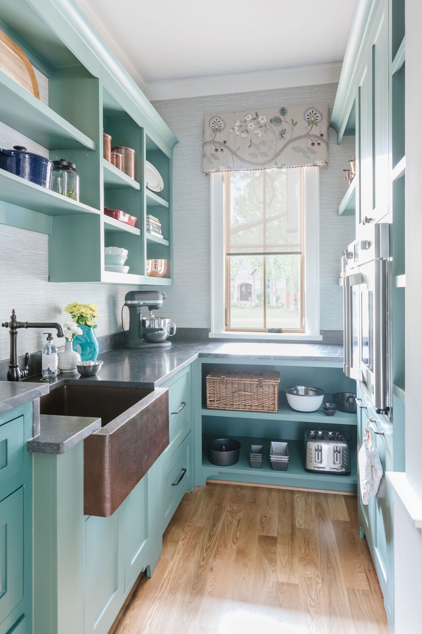 A kitchen with blue cabinets , a sink , and shelves.
