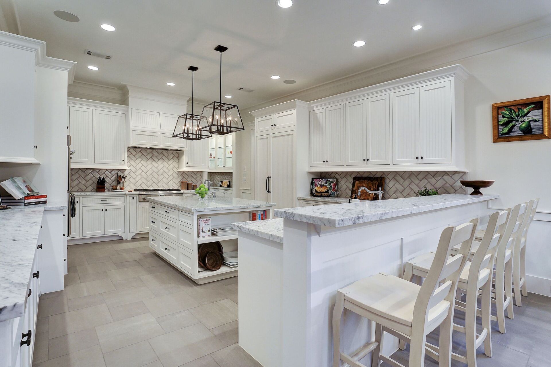 A large kitchen with white cabinets and marble counter tops.