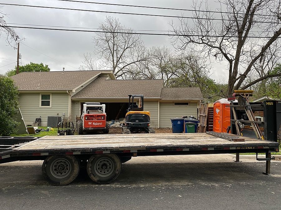 A flatbed trailer is parked in front of a house.
