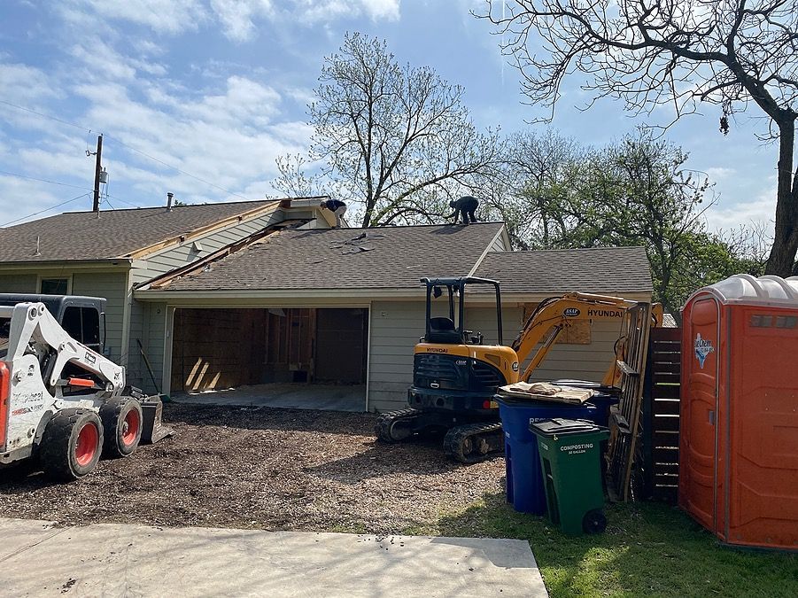A house is being remodeled with a bulldozer in the driveway.