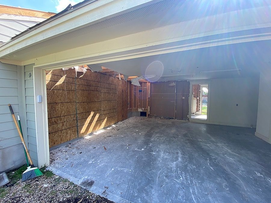 A garage under construction with the door open and a broom.