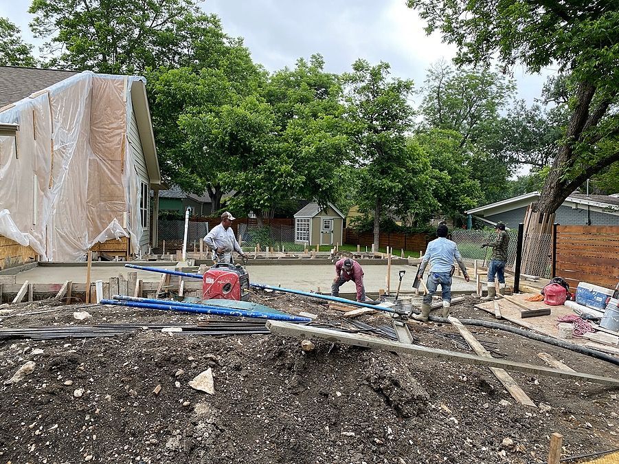 A group of construction workers are working on a construction site in front of a house.