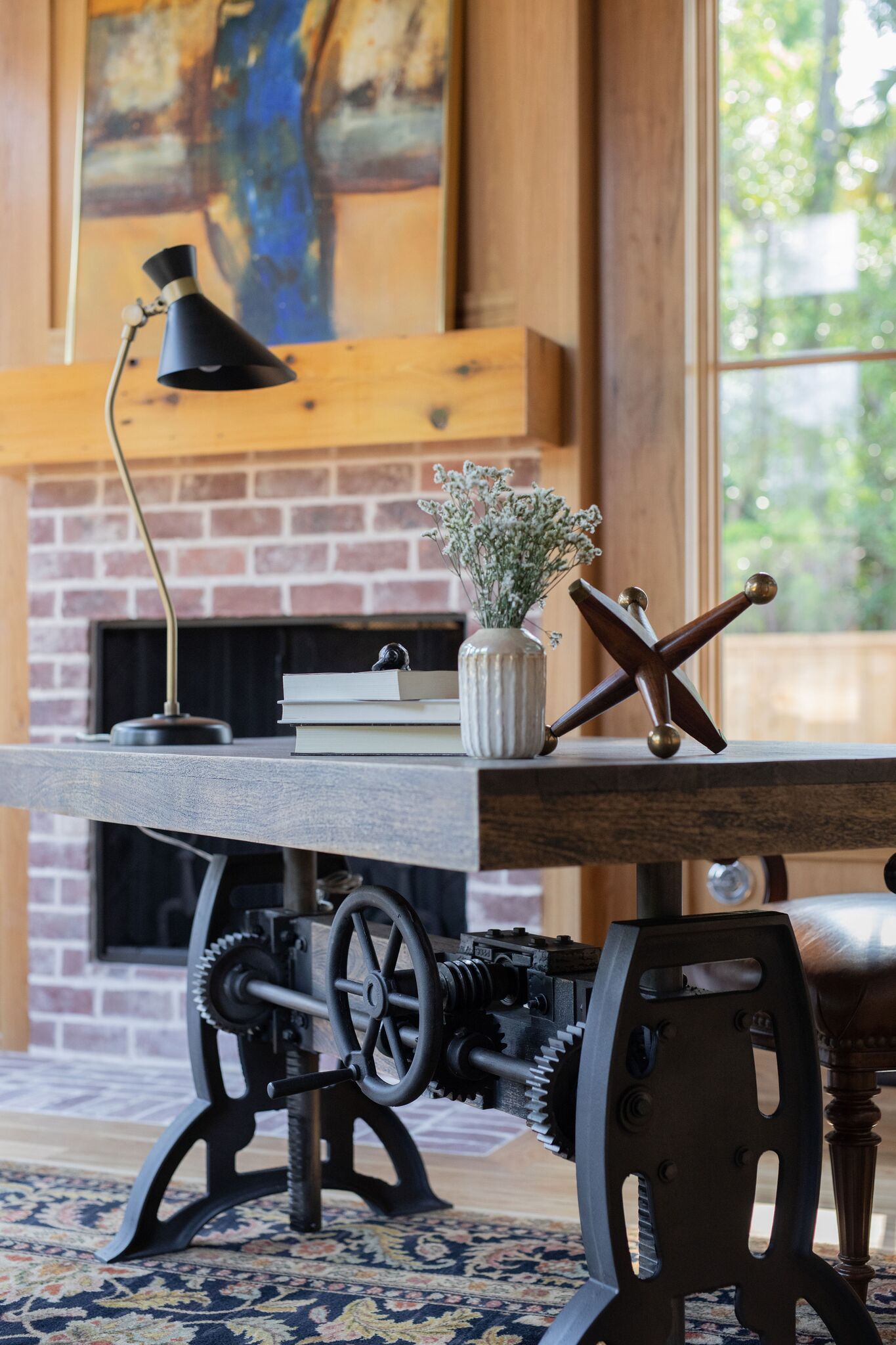 A desk with a lamp and a vase of flowers on it in a living room.