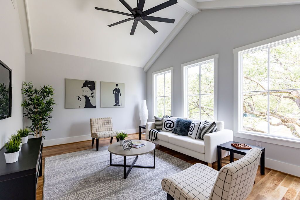 A living room with a couch , chairs , a coffee table and a ceiling fan.