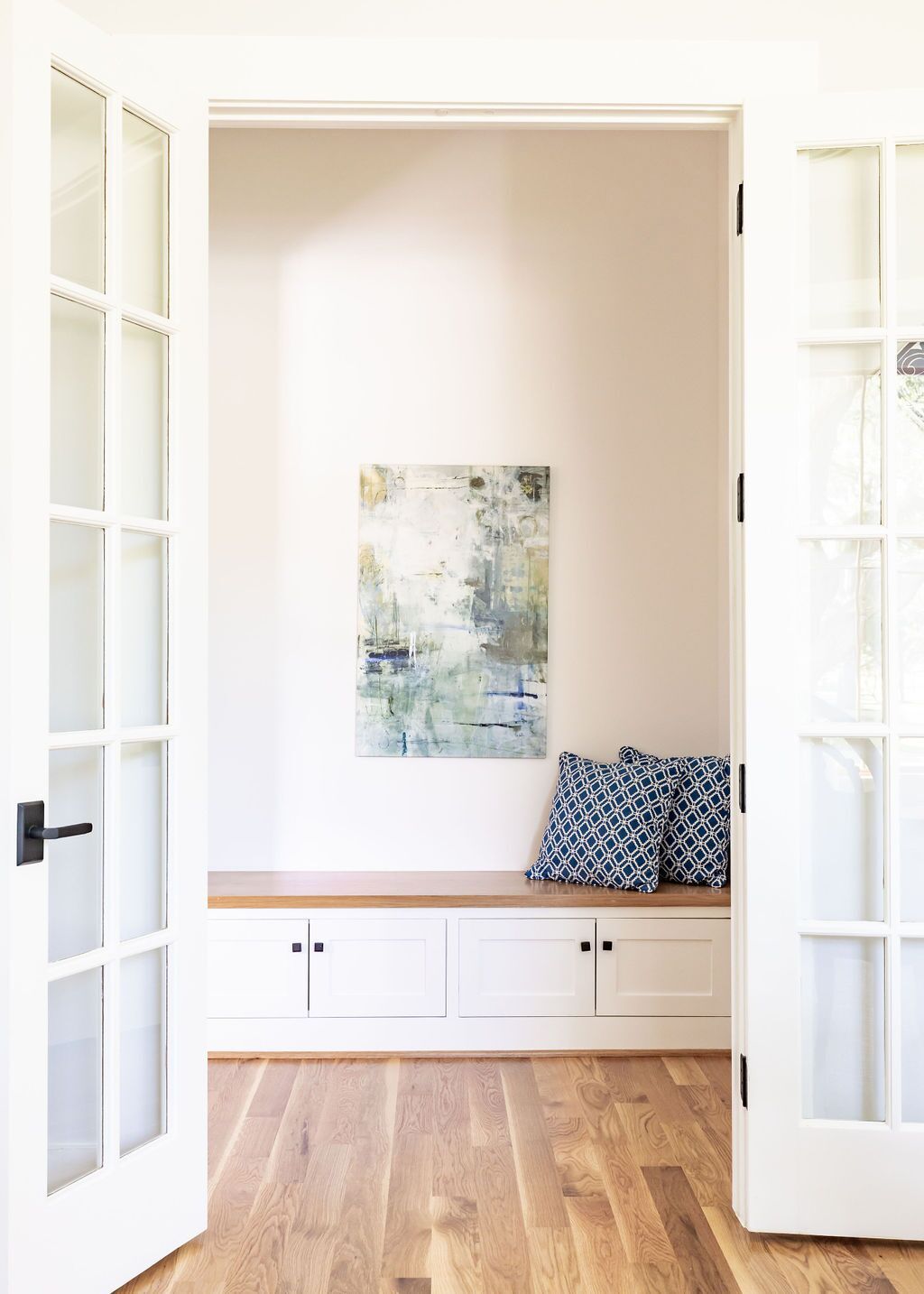 A room with a bench and a painting on the wall.