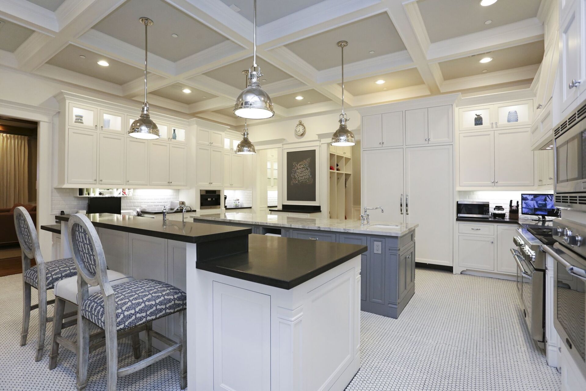 A large kitchen with white cabinets , black counter tops , and stainless steel appliances.