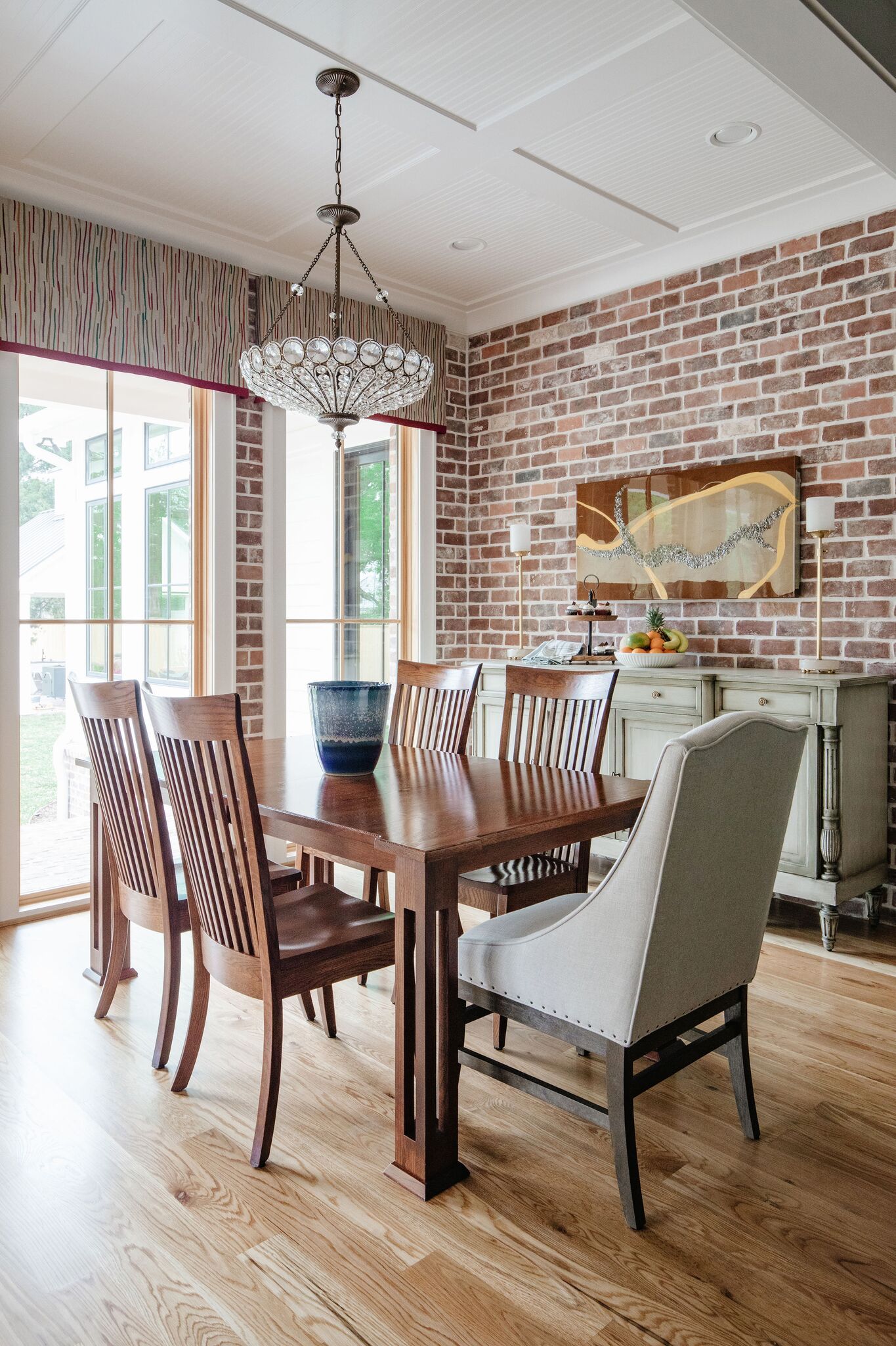 A dining room with a table and chairs and a brick wall.