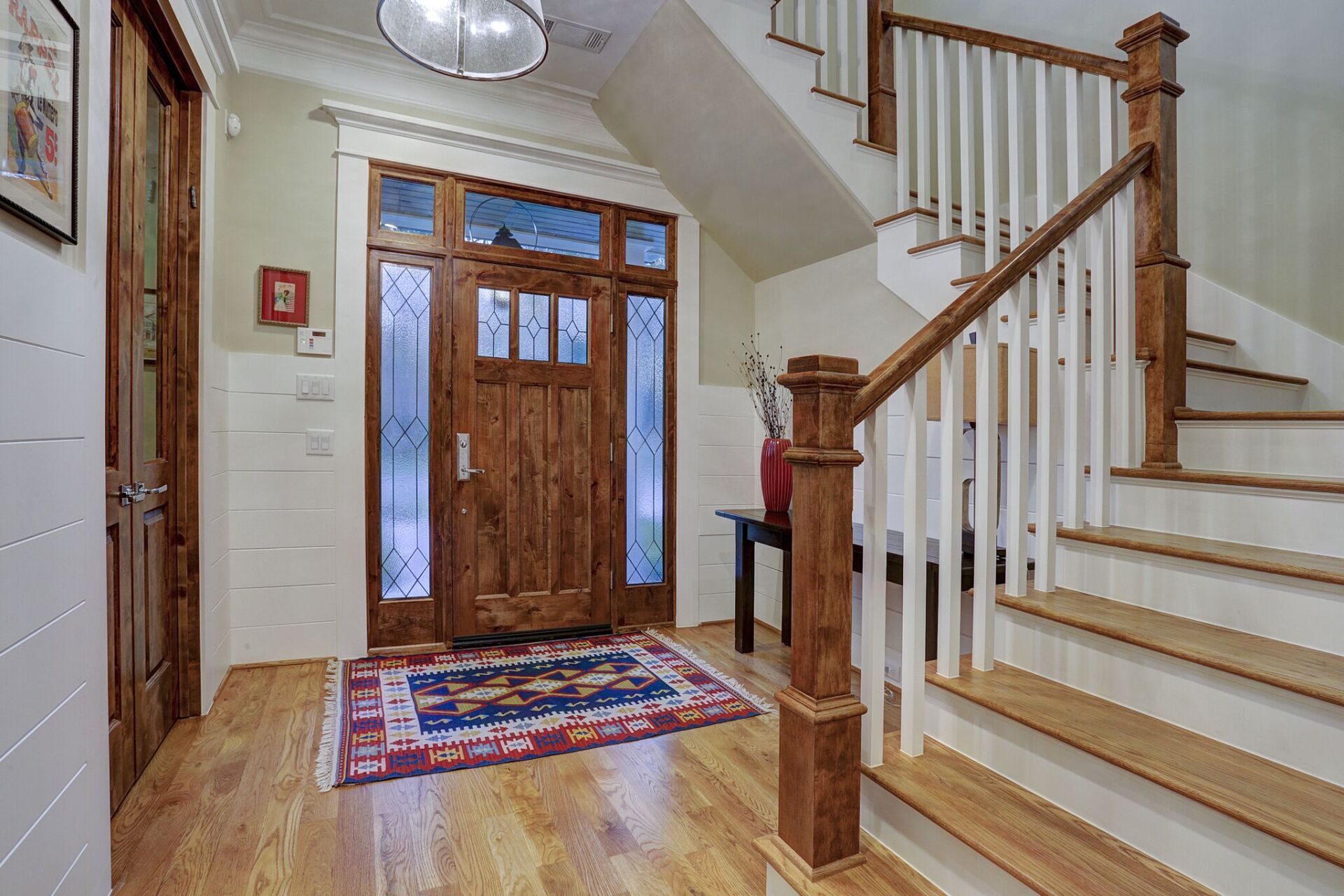 A hallway with a wooden door and stairs in a house.