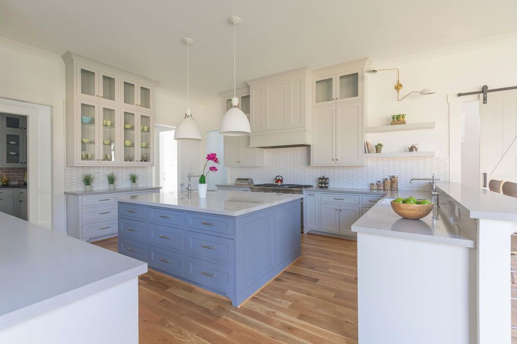 A kitchen with white cabinets and a blue island in the middle.