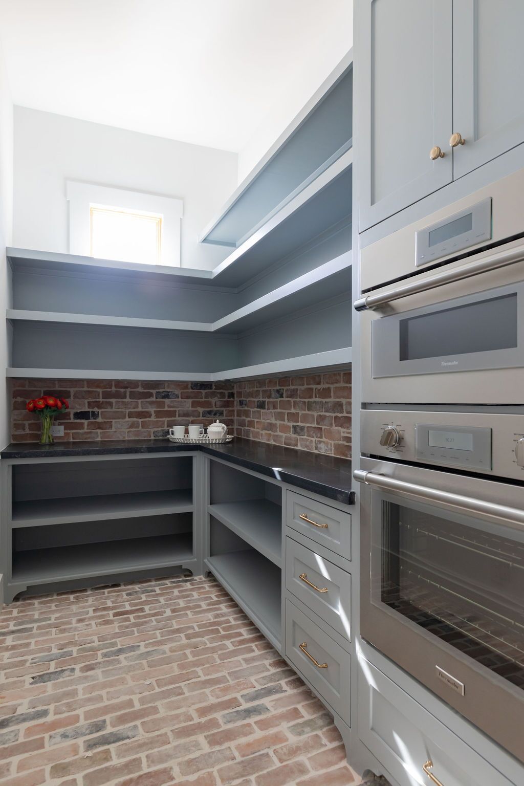 A kitchen with stainless steel appliances and brick floors.