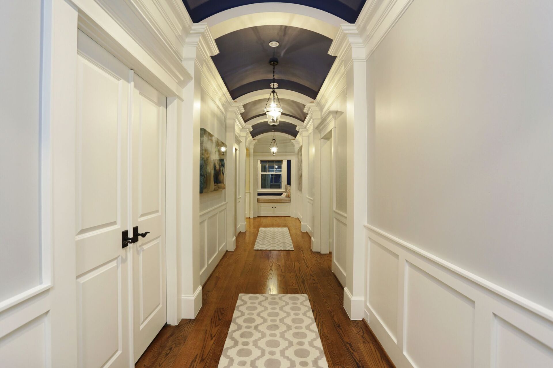 A long hallway with white doors and a blue ceiling.