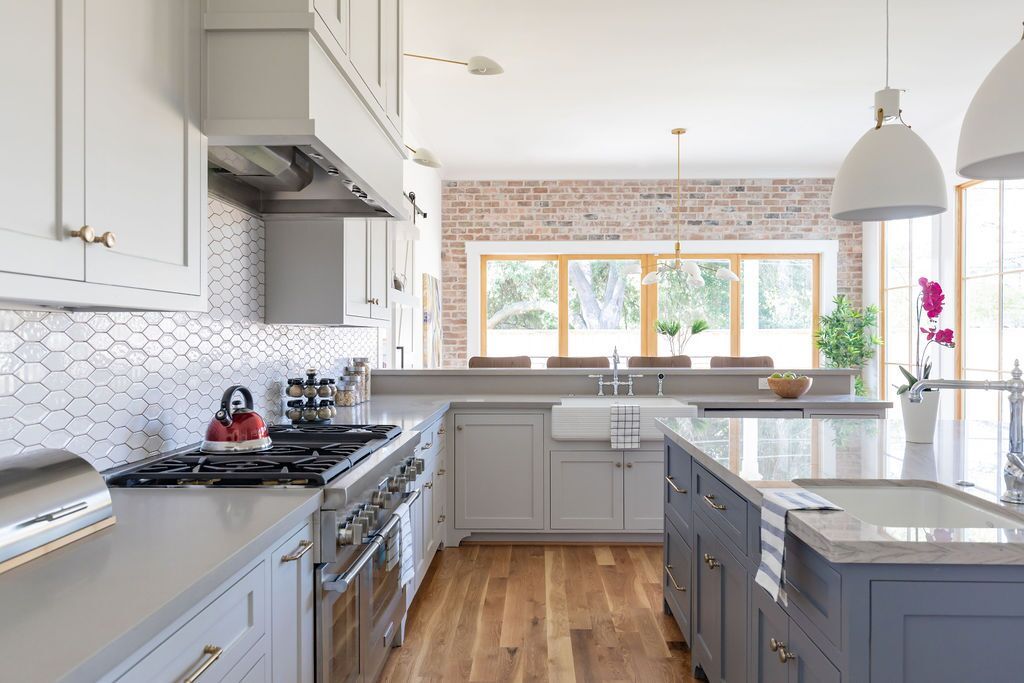 A kitchen with gray cabinets , stainless steel appliances , and a large island.