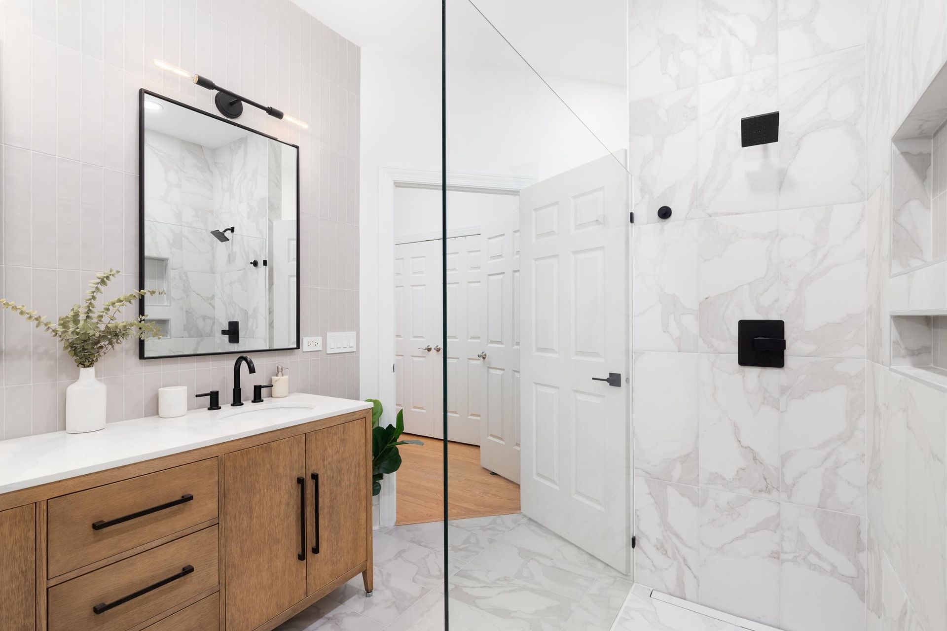 Modern white bathroom with wood vanity, mirror, walk-in shower, and tiled walls