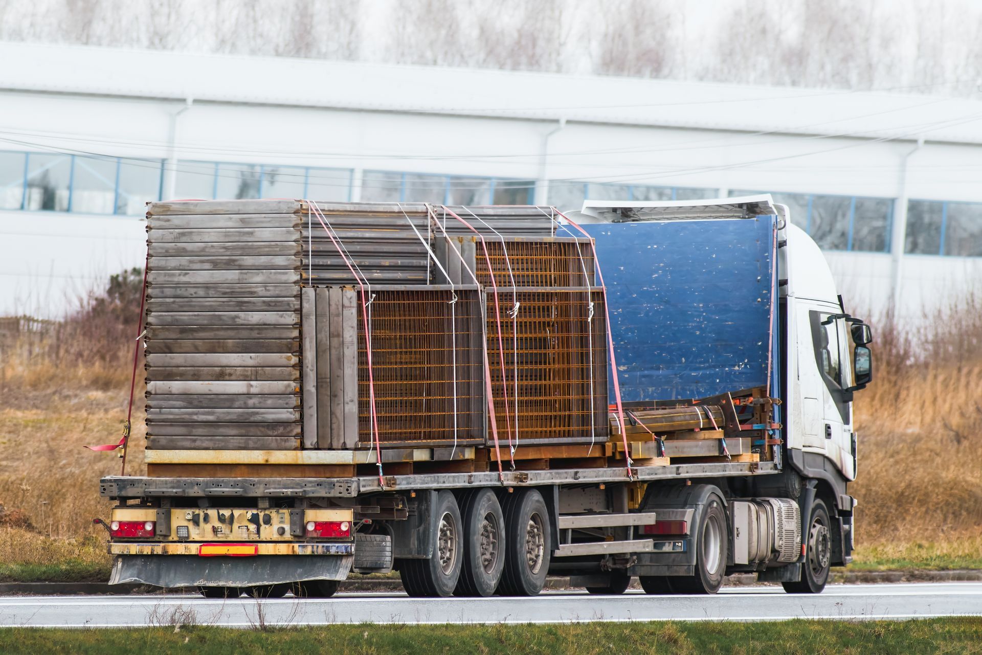 A Truck is Driving Down a Road With a Blue Tarp on the Back of It — Venus Couriers Pty Ltd In Rural View, QLD