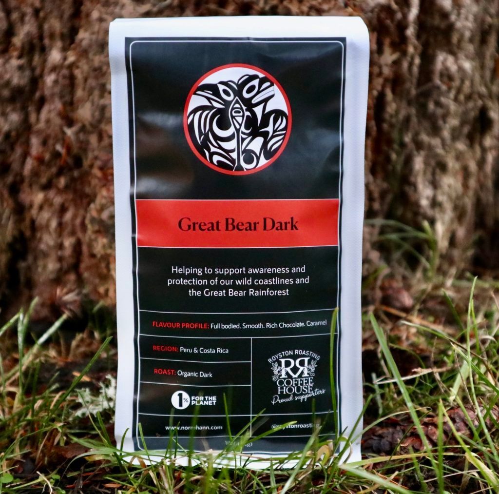 Package of Great Bear Dark coffee standing in grass outdoors with a tree trunk background