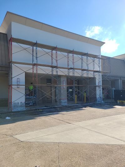 Scaffolding surrounds the exterior entrance of a commercial building under construction with a clear blue sky.