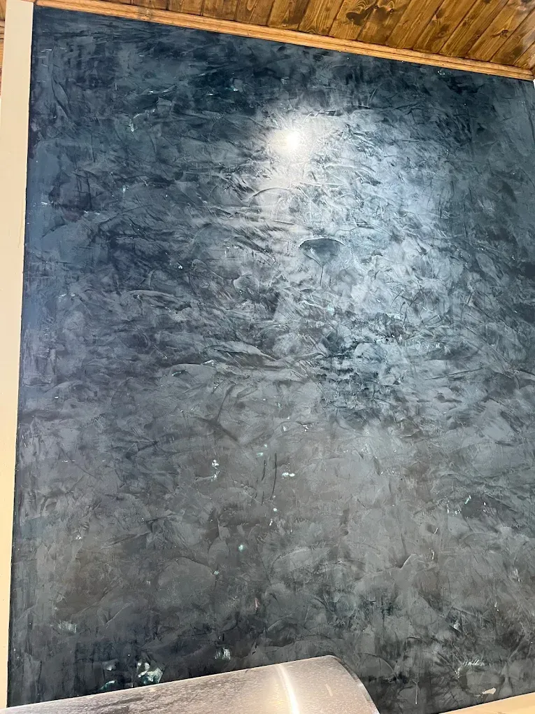 Textured dark blue-gray wall with metallic sheen, under warm lighting.