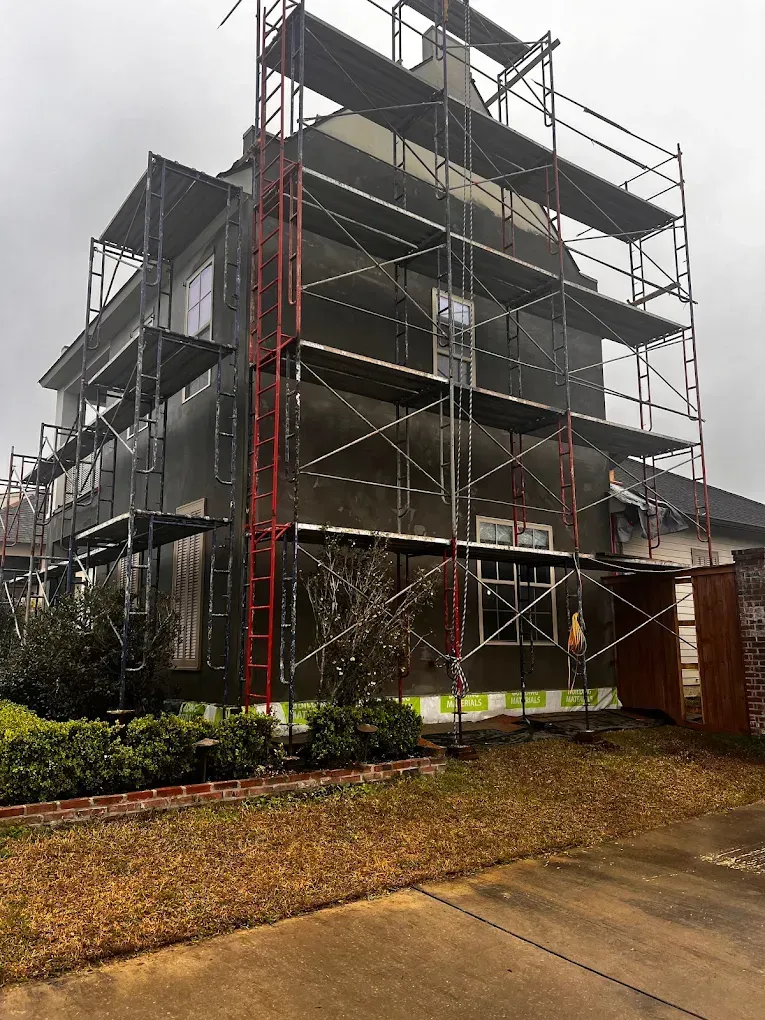 House exterior with scaffolding during siding installation; overcast day.