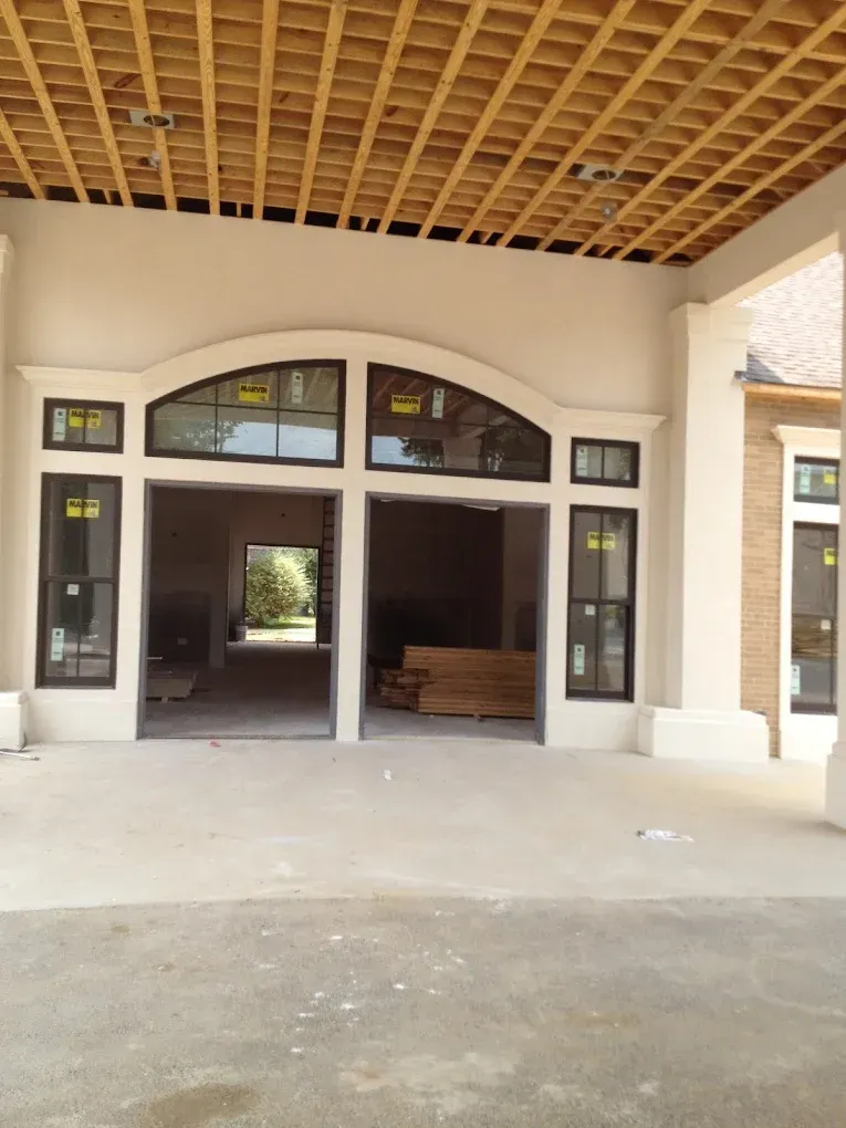 Exterior of a building under construction, featuring an arched doorway and wooden ceiling.