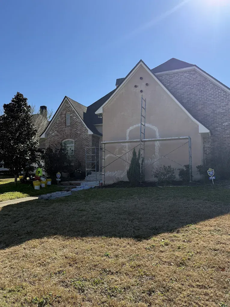House exterior under renovation with scaffolding; stucco and brick facade.