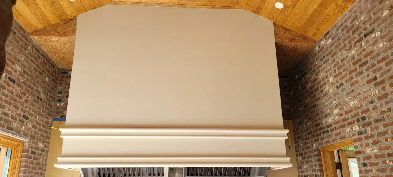 A room with exposed brick walls, a wooden ceiling, and a large white structure with ornate molding.