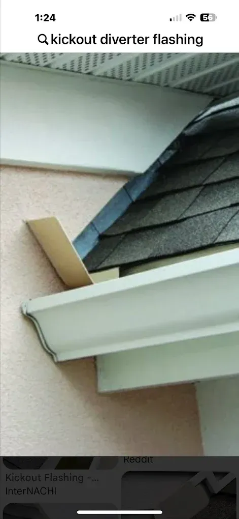 A kickout flashing diverts water away from the wall. Beige wood is attached to the wall and roof.