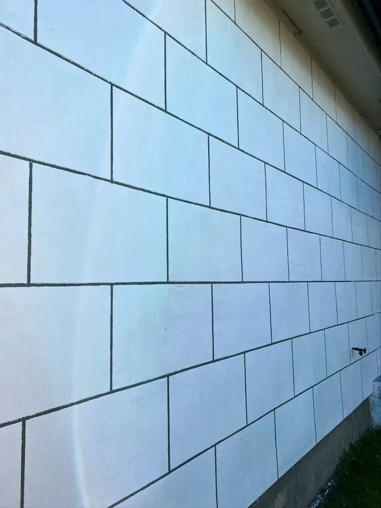 White brick wall with dark mortar joints, seen from a low angle.