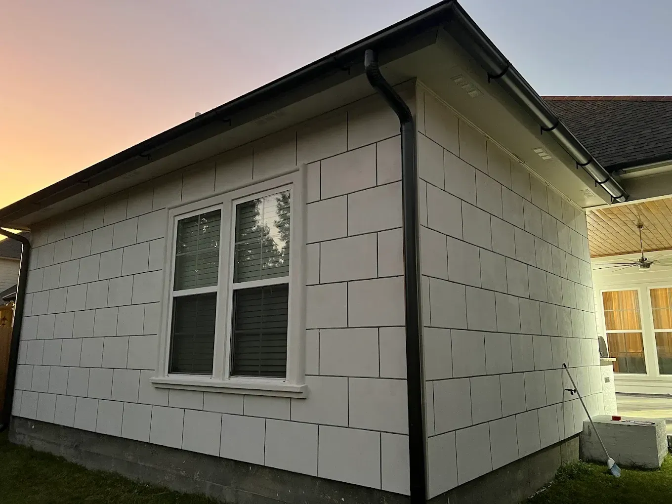 White-sided shed with a window and black trim under an evening sky.