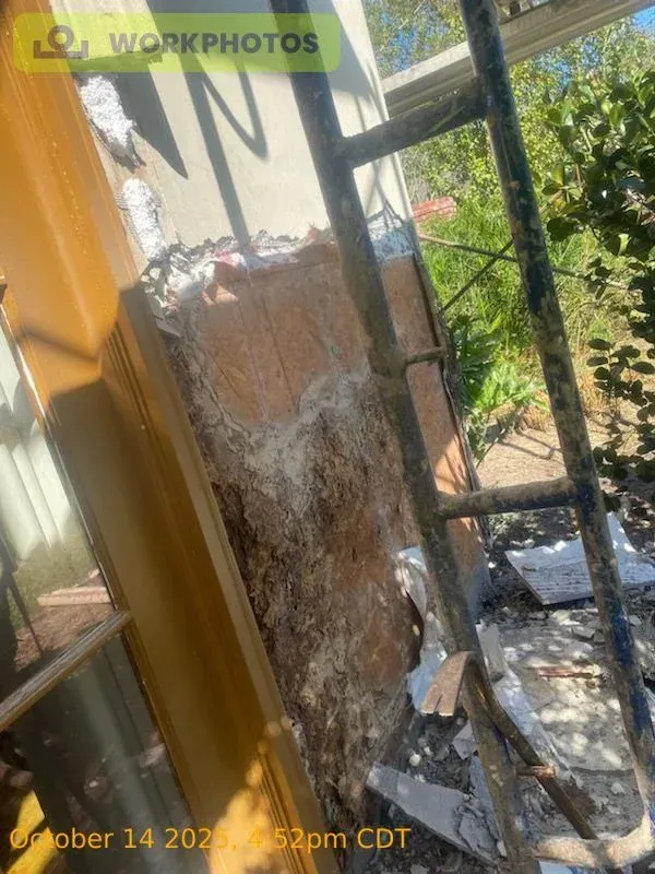 Wall damage with exposed insulation, next to a ladder and window frame.