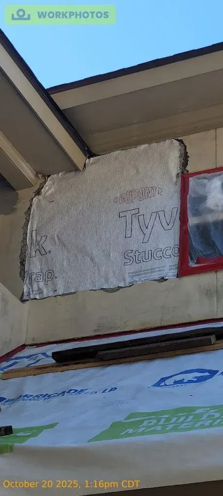 Exterior house wall repair with Tyvek wrap and exposed insulation.