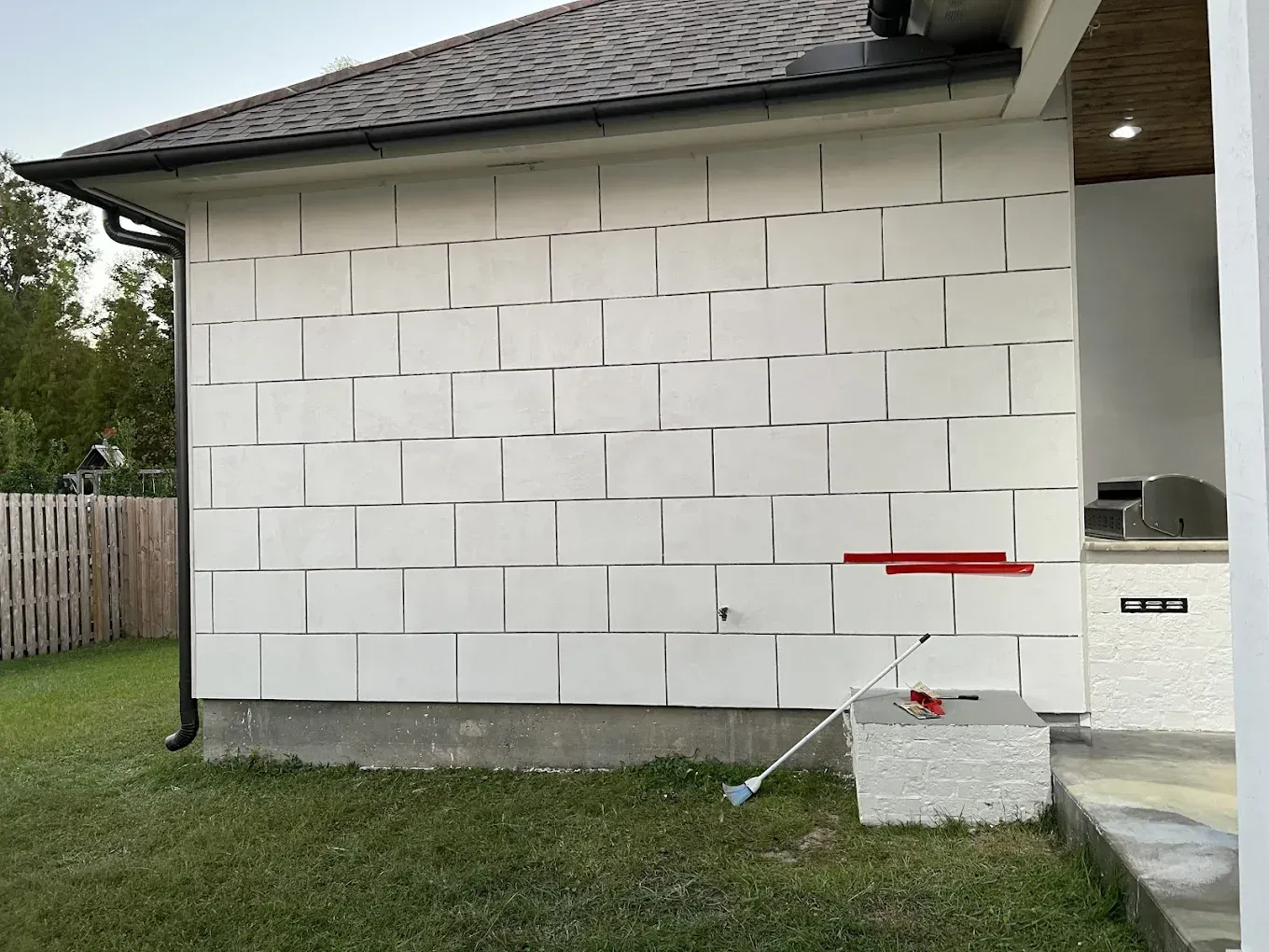 White brick wall of a house under construction; red levels and tool on blocks.