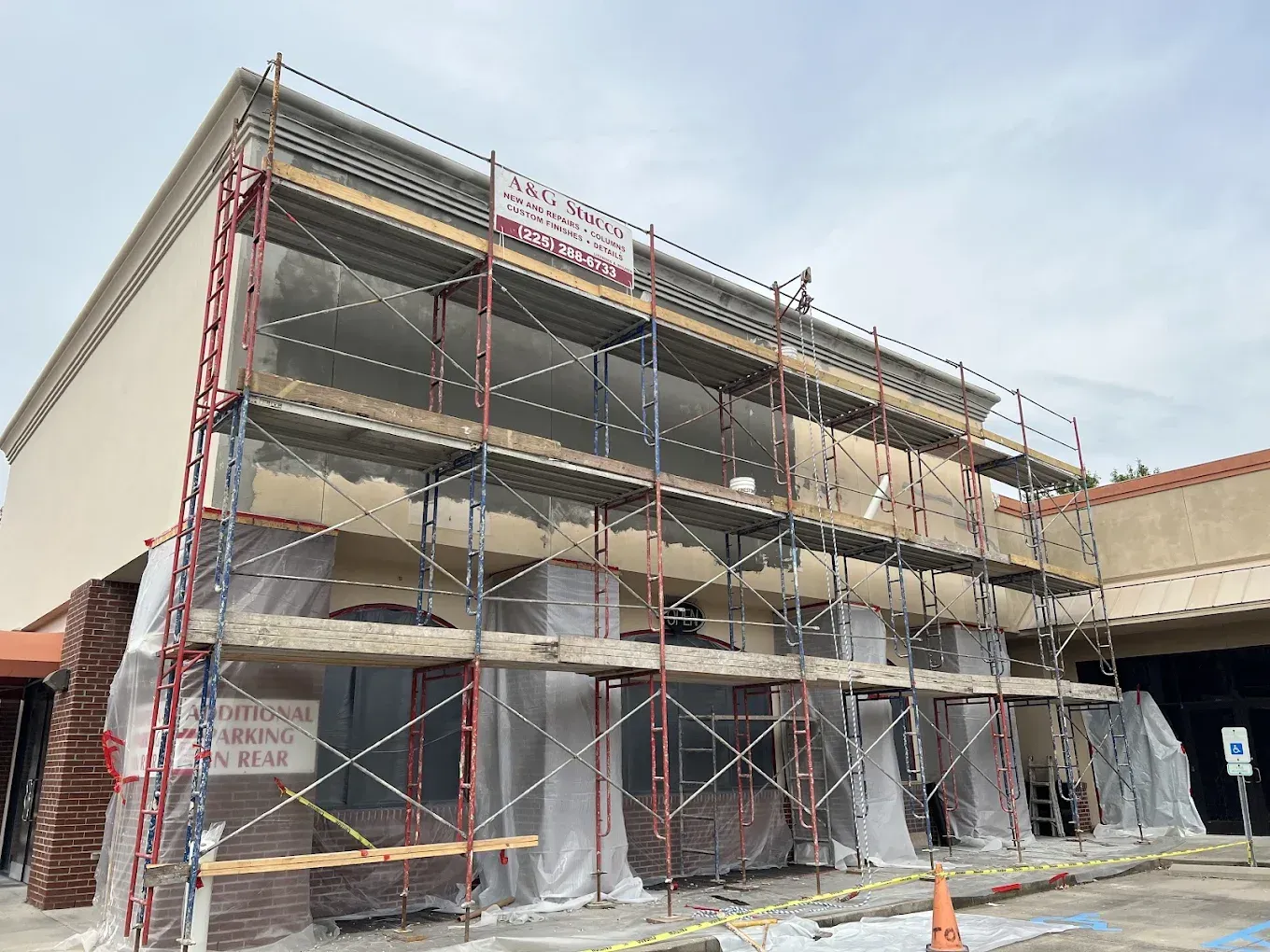 Building facade under renovation, scaffolding, beige exterior, overcast sky.
