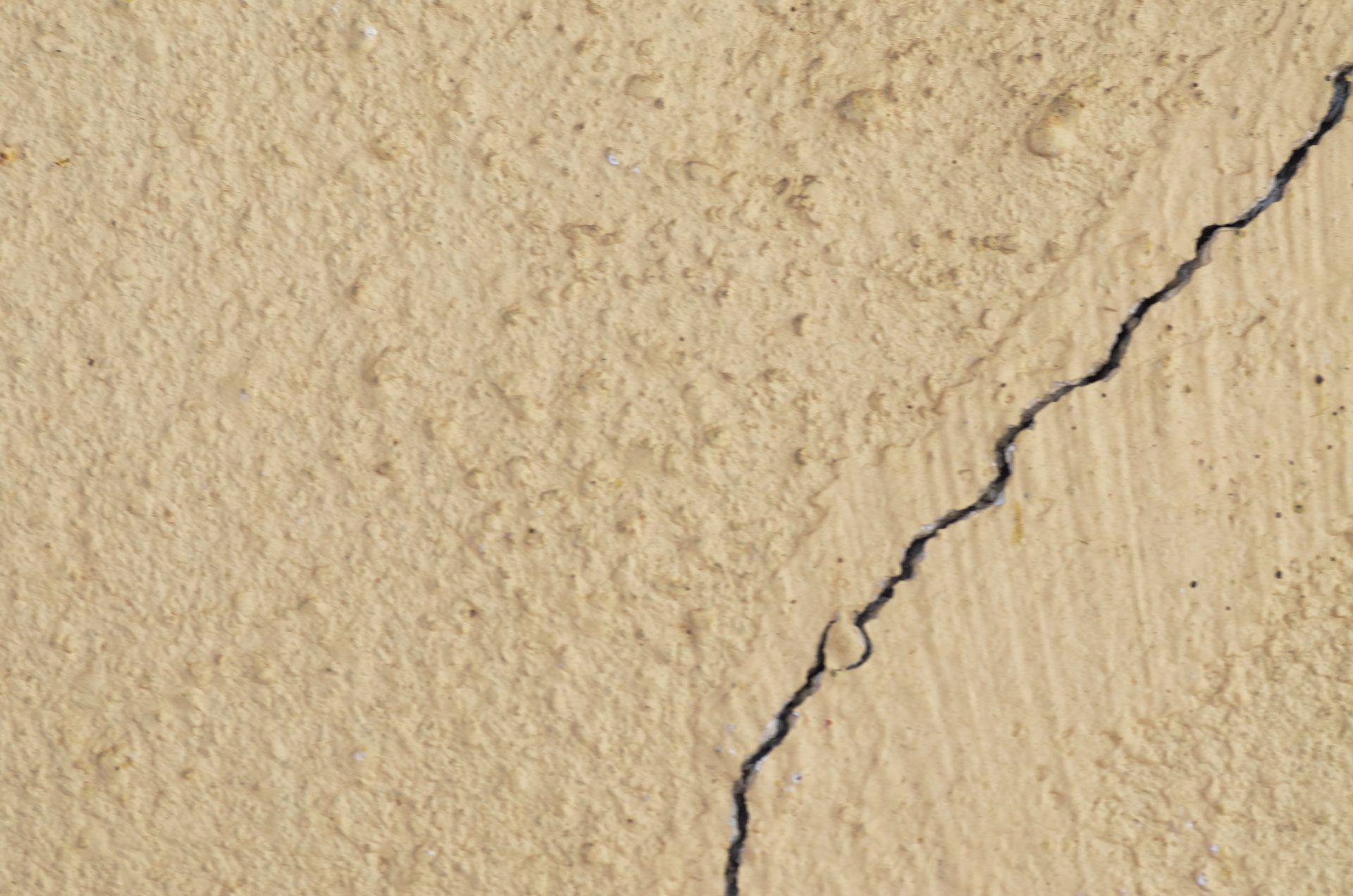 Beige concrete wall with a prominent diagonal crack.