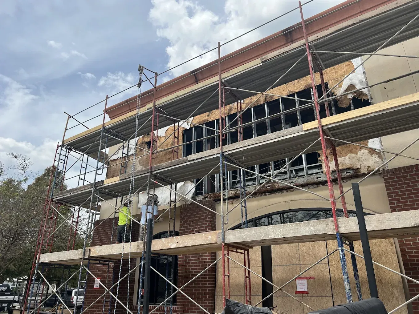 Building under construction with scaffolding; a worker is visible.