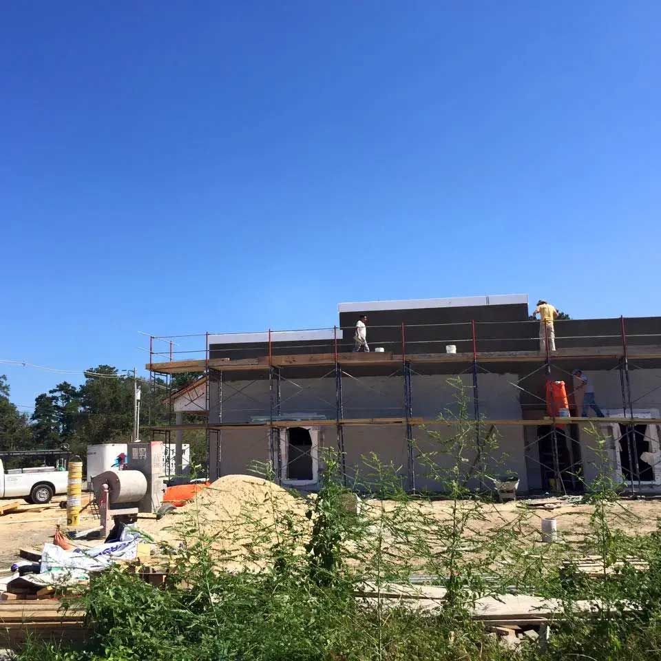 A building is being built with scaffolding and a blue sky in the background.