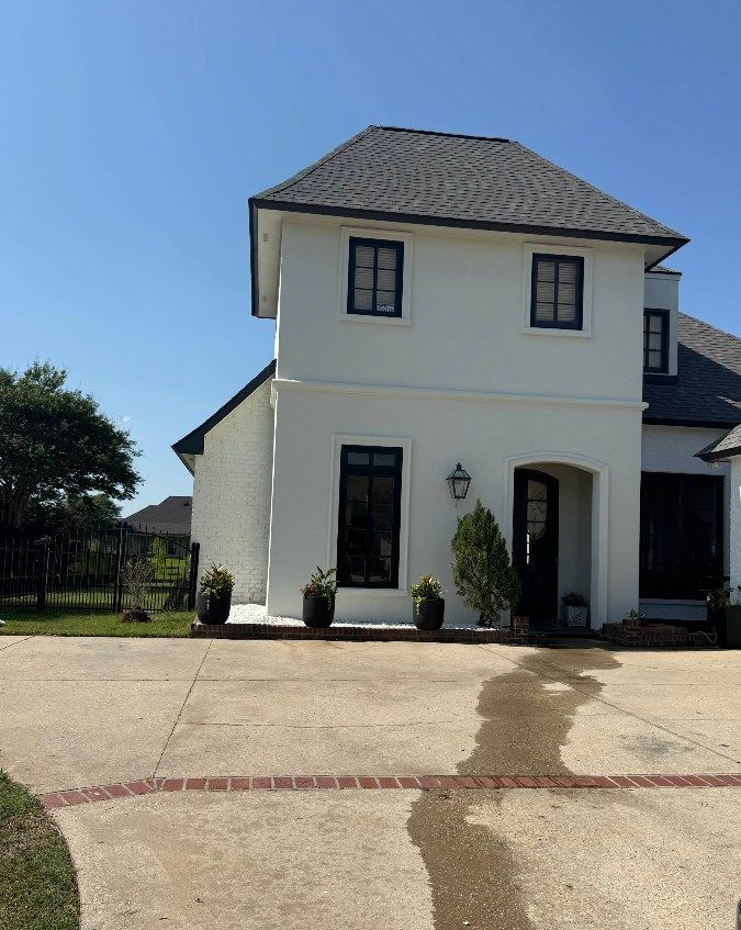 A white house with a gray roof and a driveway.